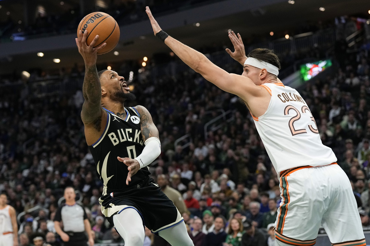 Dec 19, 2023; Milwaukee, Wisconsin, USA; Milwaukee Bucks guard Damian Lillard (0) shoots around San Antonio Spurs center Zach Collins (23) during the first quarter at Fiserv Forum.